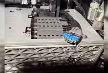 Gros plan de la Radeon RX 9070 XT NITRO+ avec un adaptateur 12V-2×6 bleu présentant des traces de brûlure au connecteur d’ali