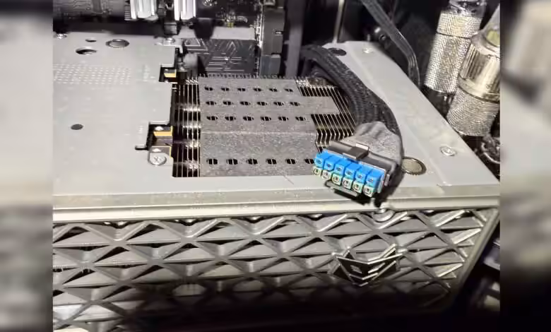 Gros plan de la Radeon RX 9070 XT NITRO+ avec un adaptateur 12V-2×6 bleu présentant des traces de brûlure au connecteur d’ali