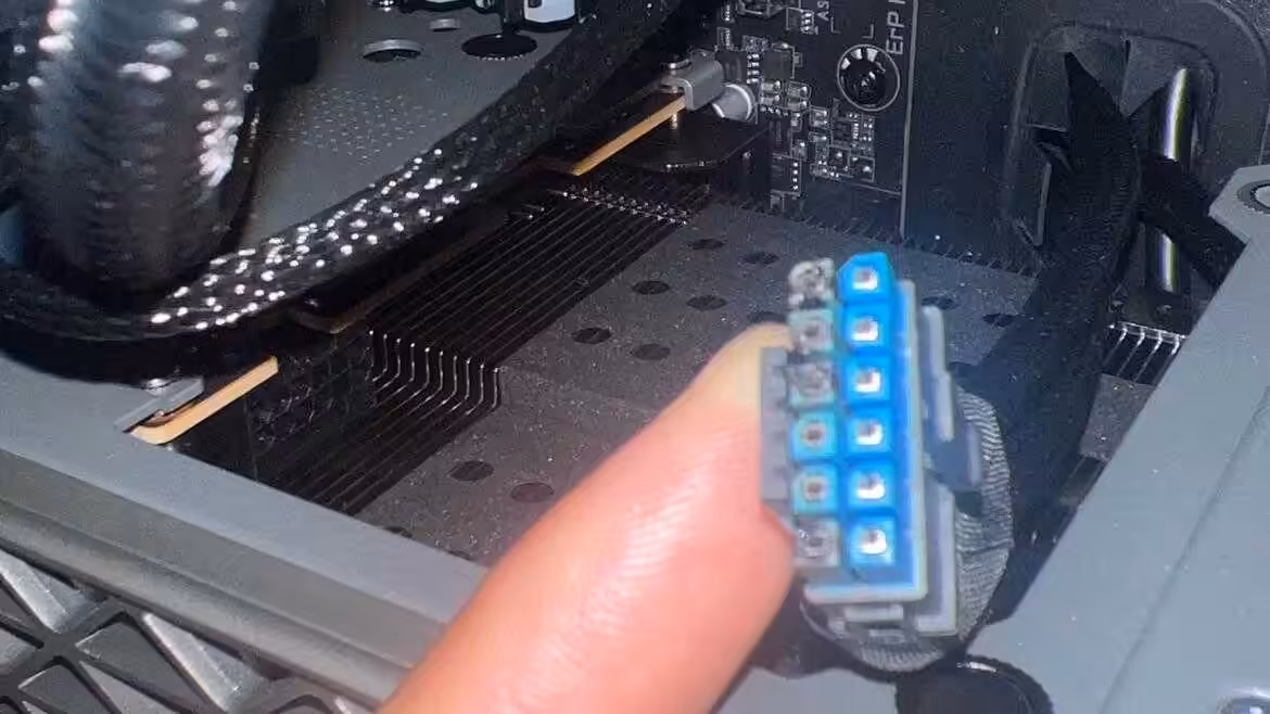 Gros plan du connecteur 12V-2×6 bleu de la Radeon RX 9070 XT NITRO+ montrant des traces de brûlure et de chauffe sur les broc