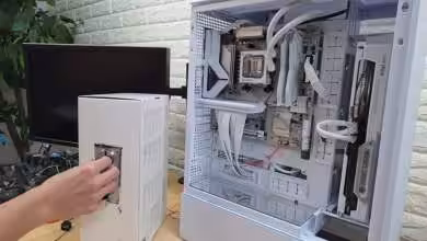 Photo montrant un PC modifié avec un monnayeur intégré, où l’insertion d’une pièce déclenche l’allumage du bouton Power.