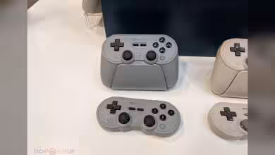 Manettes 8BitDo grises modernes posées sur une table d'exposition.