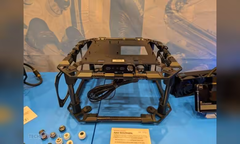 Alphacool CES 2026 : benchtable carbone, radiateur externe 1260 et nouveaux fittings 1 Benchtable carbone Alphacool avec cadre noir exposé sur table bleue.