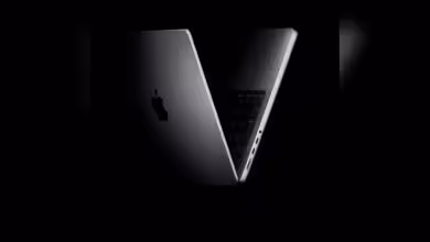 MacBook Apple ouvert en vue arrière sur fond noir.