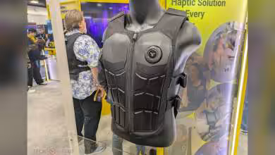 Mannequin portant le gilet bHaptics TactSuit avec design gaufré noir au salon de la technologie.