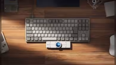 Trackball Keychron Nape Pro intégré à un clavier gris sur bureau en bois.