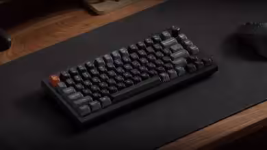 Keychron V Ultra 8K : claviers mécaniques 75/80/100 %, triple sans‑fil 8 kHz 14 Clavier mécanique Keychron sur bureau en bois, touches noires et grises, touche orange distinctive.