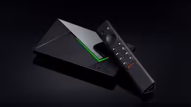 Box NVIDIA SHIELD TV noire avec télécommande, design angulaire, éclairage vert visible.