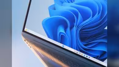 Ordinateur portable avec Windows 11 affiché à l'écran, fond d'écran bleu distinctif.