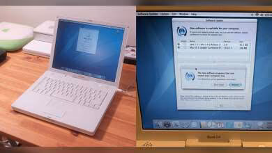 Apple iBook G4 blanc sur bureau en bois montrant écran de mise à jour logicielle.