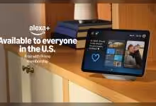 Écran smart Amazon Echo Show affichant Alexa+ sur une étagère en bois, montre applications et messages.