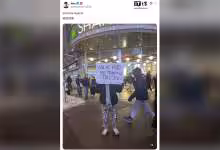 Personne tenant une pancarte, devant un restaurant Shake Shack.