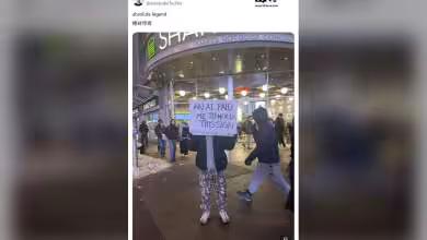 Personne tenant une pancarte, devant un restaurant Shake Shack.