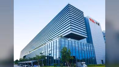 Bâtiment moderne avec logo TCL, architecture vitrée et végétation, ciel dégagé