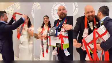 Un couple de mariés recevant une boîte cadeau ornée d'un ruban rouge avec une mention RTX 5090.