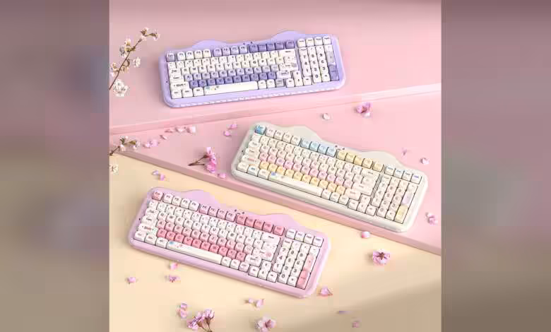 YUNZII C98 Cake Meow : clavier mécanique 96 % tri-mode avec pavé numérique 1 Trois claviers mécaniques YUNZII C98 Cake Meow colorés sur fond rose.