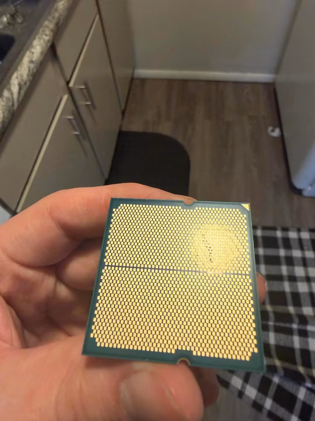 Vue arrière d’un processeur AMD Ryzen en main, détails des connecteurs dorés.