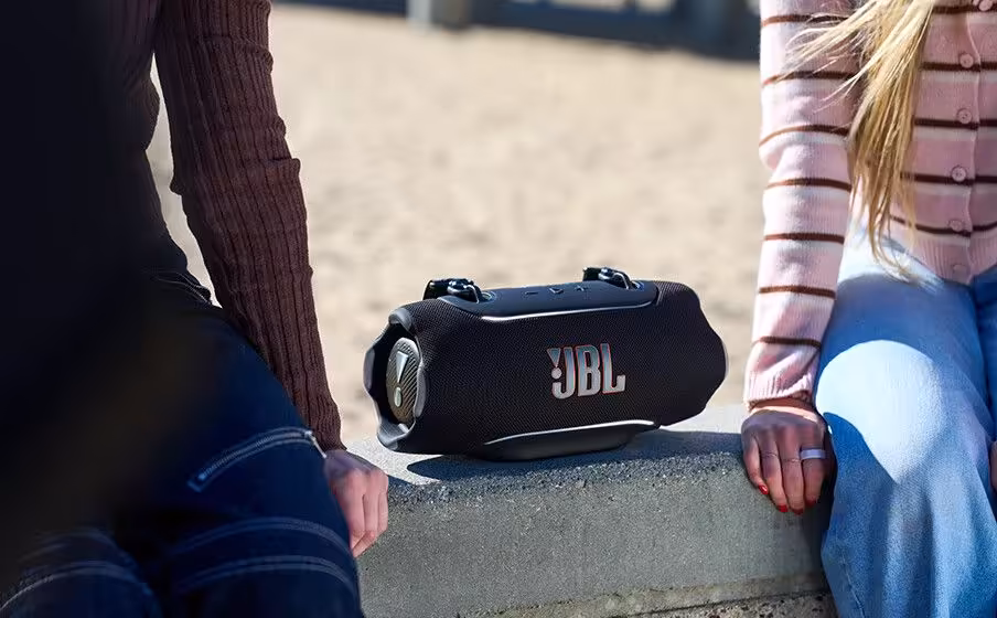 Enceinte JBL Xtreme 5 posée entre deux personnes assises.