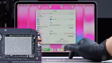 MacBook avec écran rose, main gantée naviguant sur l'interface interne