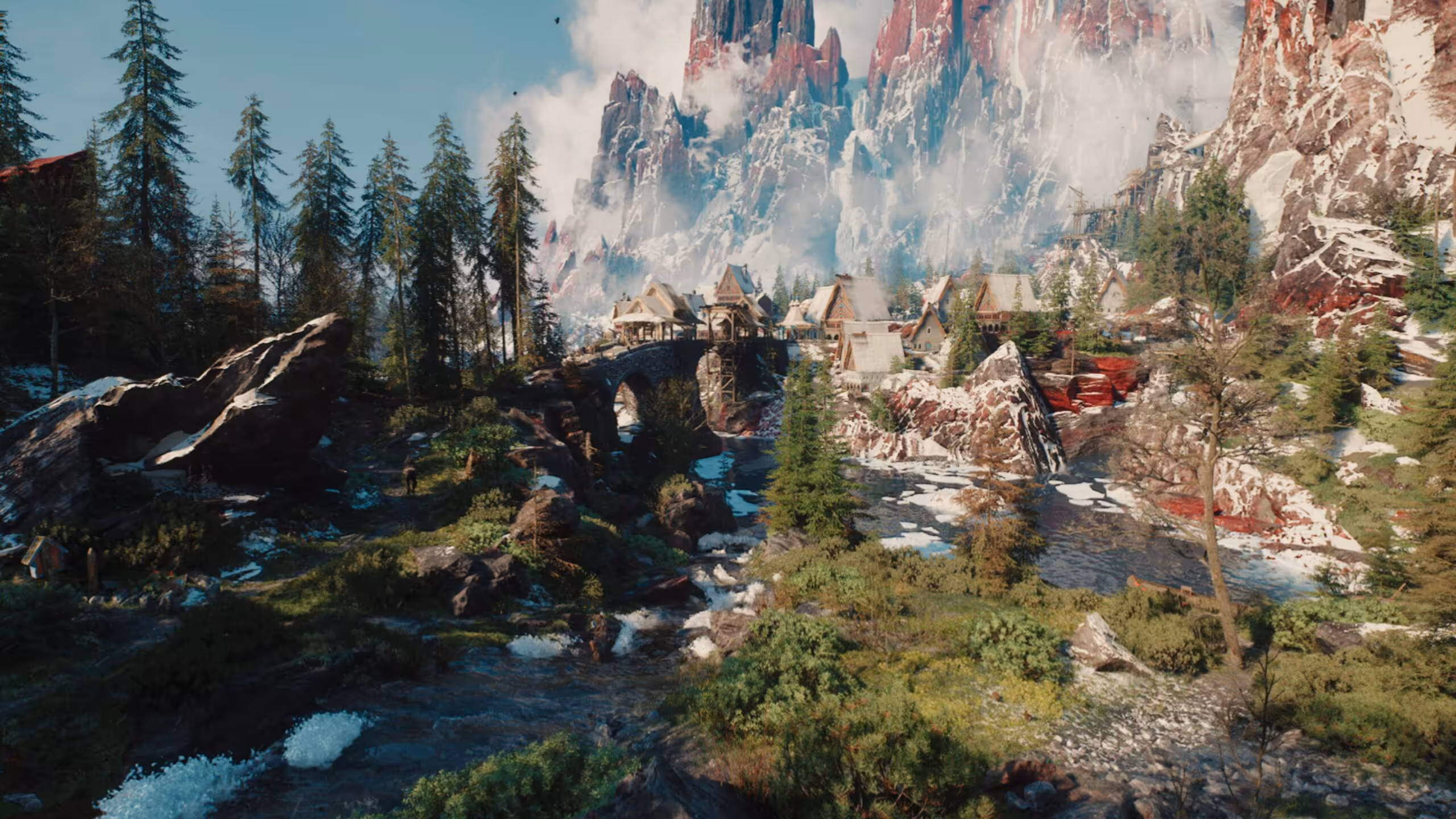 Village en montagne entouré de forêts et sommets enneigés sous un ciel bleu vif.