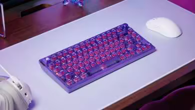 Clavier Corsair K65 Plus Wireless Atomic Purple sur bureau avec accessoires gaming.