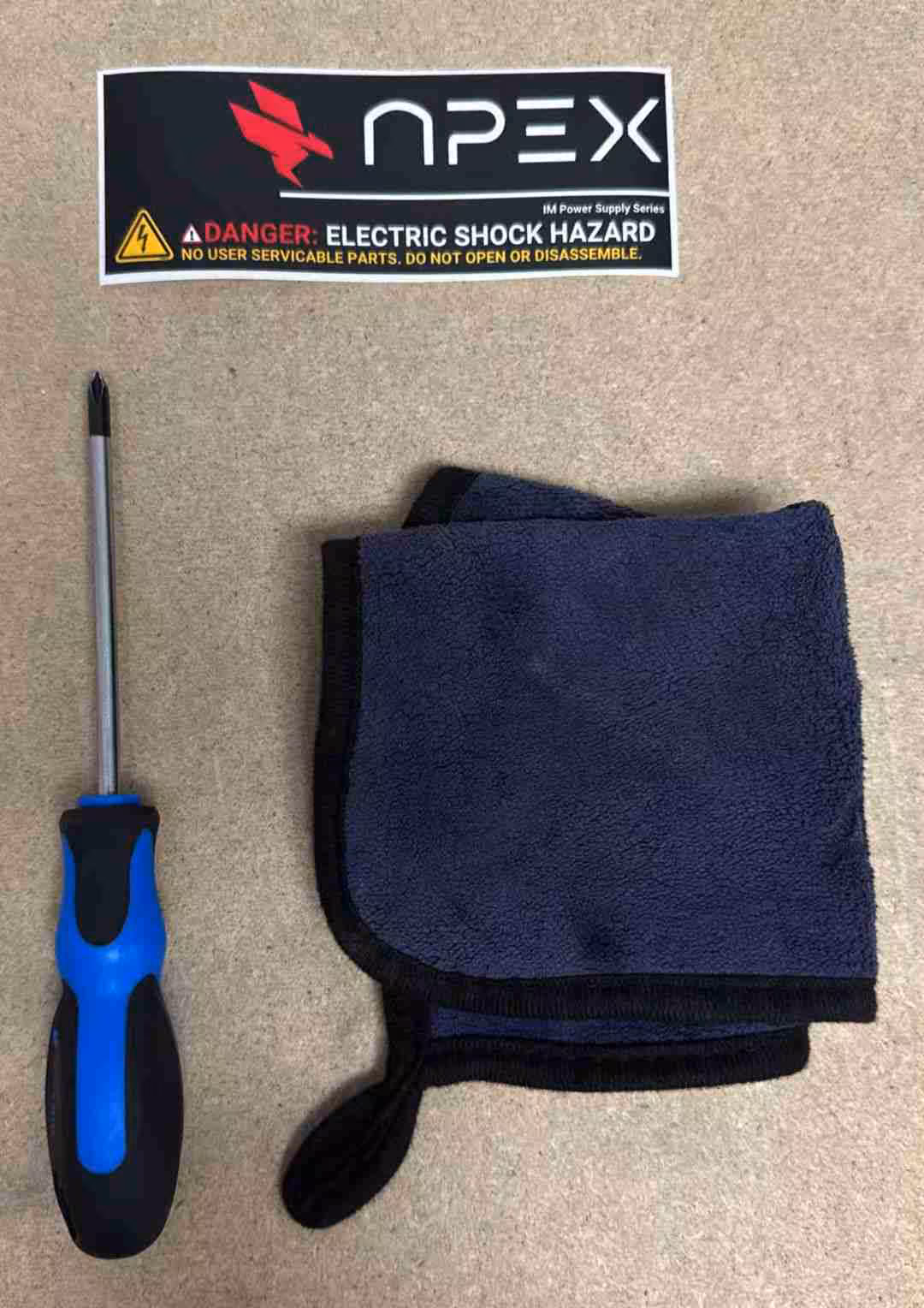 Photo d'un tournevis sur tissu avec logo Apex danger fond beige