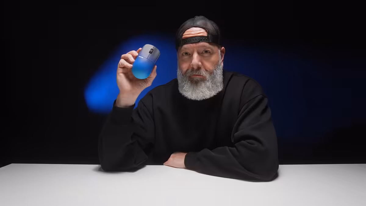Homme tenant une souris Pulsar X2H CrazyLight BadSeed Tech Edition contre un fond sombre.