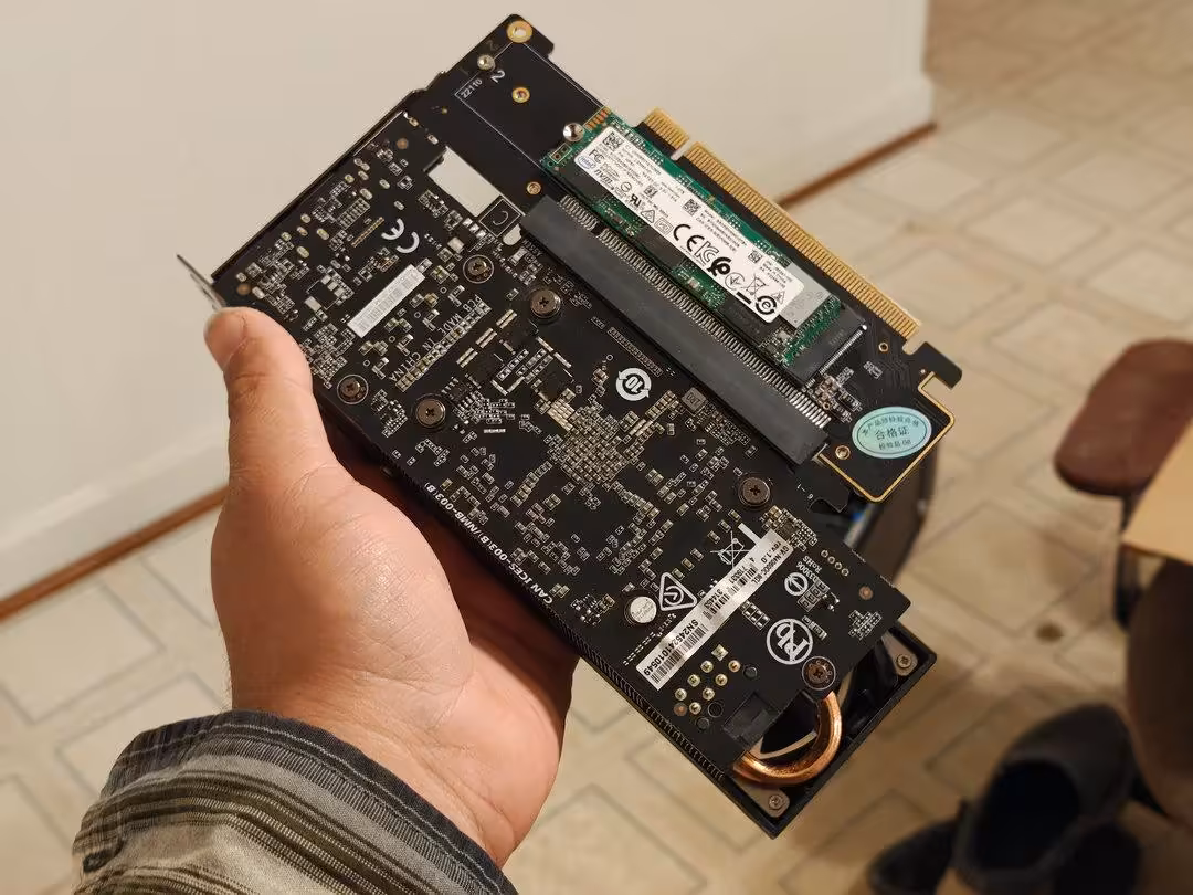 Carte PCIe dans une main, environnement intérieur peu éclairé, amateur.