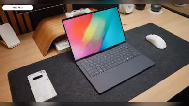 Ordinateur portable Dell XPS 14 sur bureau avec clavier éclairé, fond neutre et contrasté.