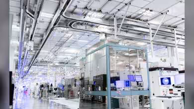 Intérieur d'une salle blanche de fabrication de semi-conducteurs, machines industrielles visibles.