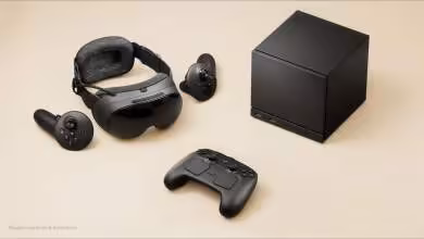Console de jeu noire avec casque VR, deux manettes et une télécommande sur fond beige.