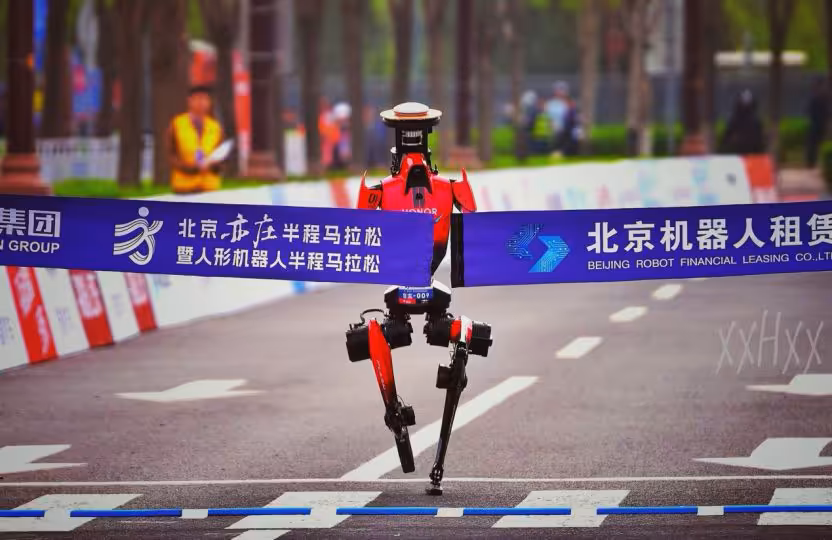 Robot humanoïde Honor franchissant la ligne d'arrivée d'une course avec bannière.