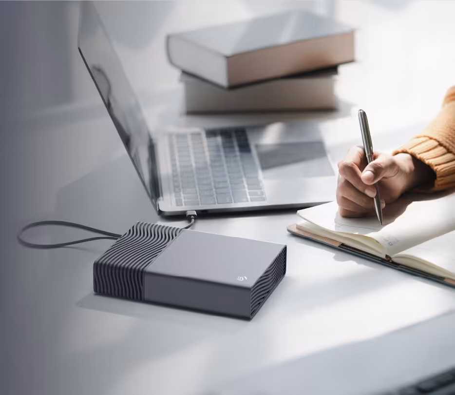 Disque dur sur un bureau à côté d'un ordinateur portable et d'un carnet.