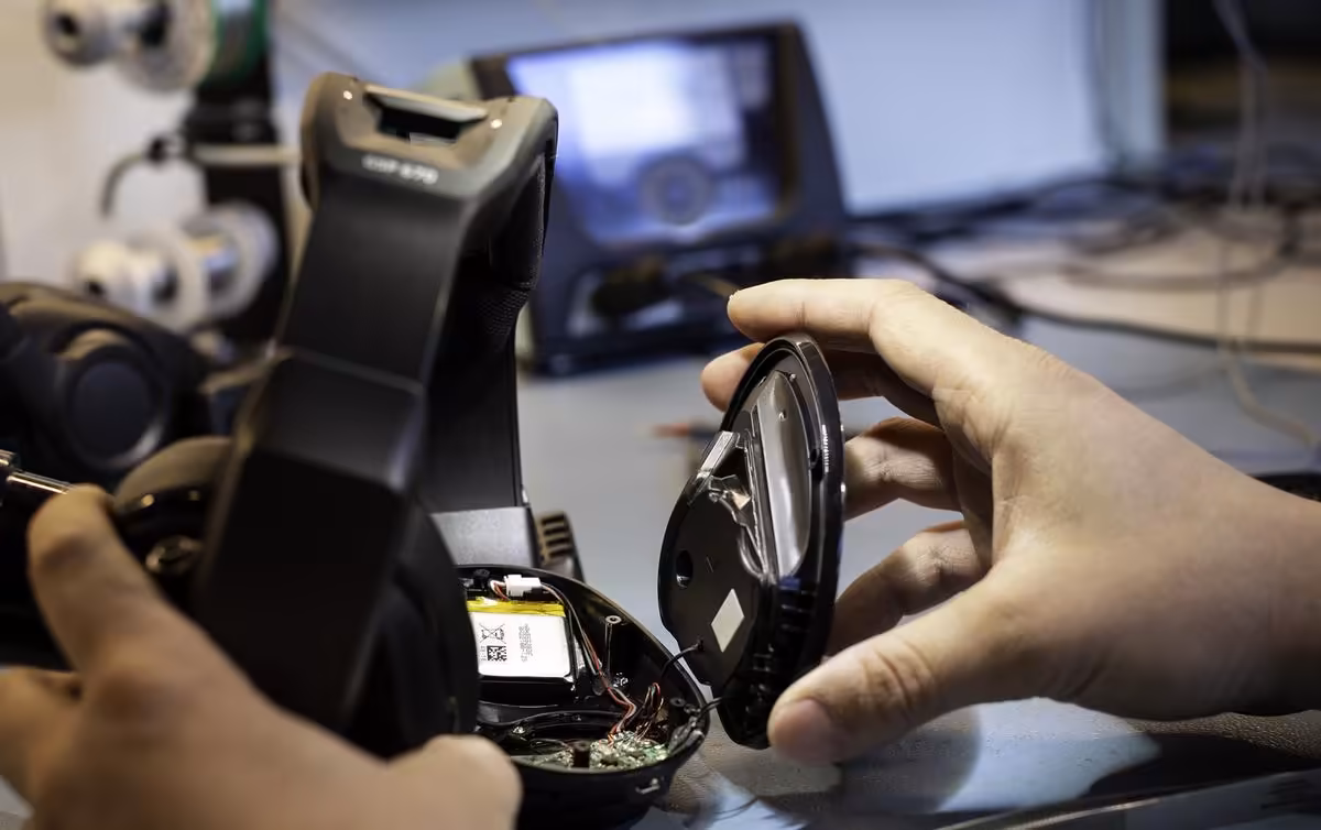 Casque EPOS ouvert en réparation, batterie remplacée à la main dans un atelier
