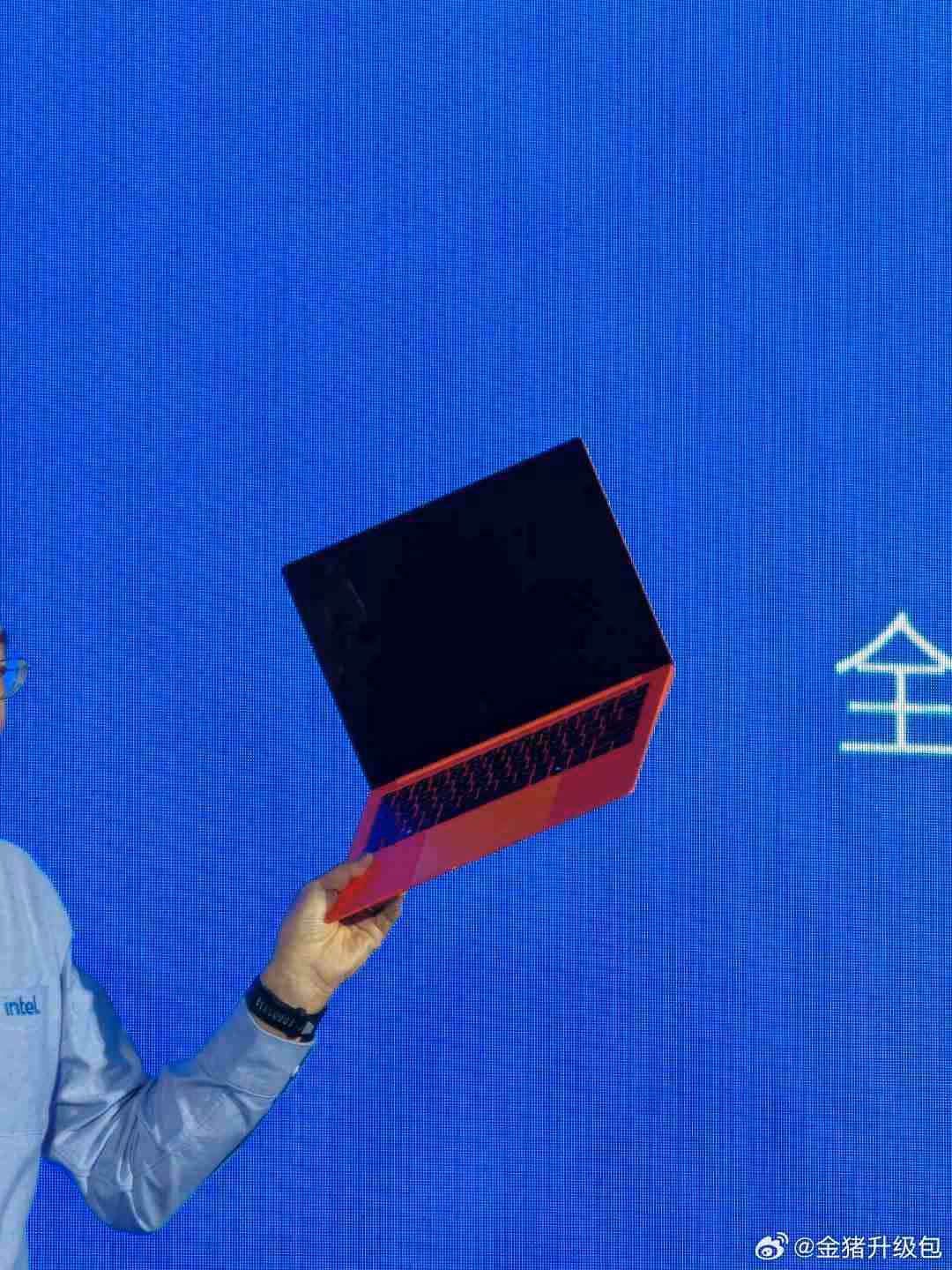 Ordinateur portable rouge levé sur scène, fond bleu écrasant.