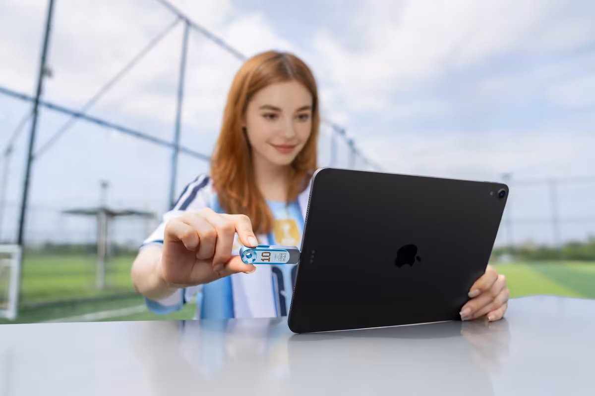Jeune femme utilisant une clé USB Lexar avec un iPad sur un terrain de sport