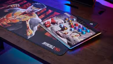Stick arcade Corsair Invincible VS posé sur tapis de bureau assorti, éclairage RGB violet et bleu