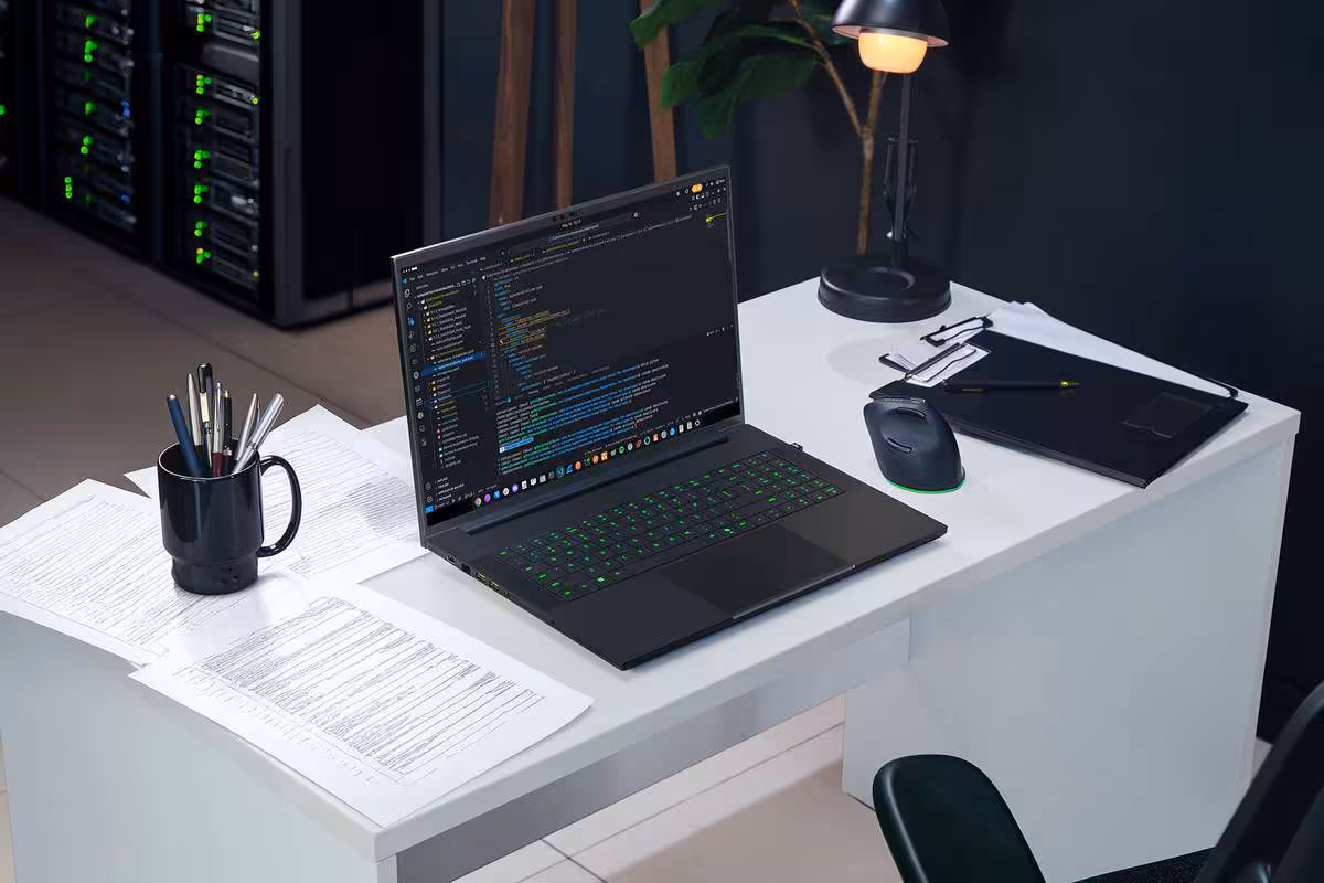 Razer Blade 18 2026 : un 18 pouces taillé pour le jeu AAA et l’IA locale 5 Razer Blade 18 sur bureau, écran affichant du code dans un environnement de travail