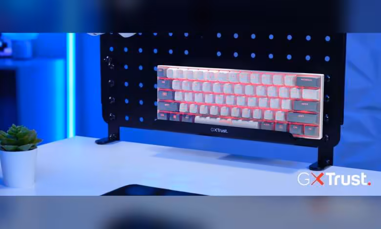Acira Tri-Mode, le clavier 60 % sans-fil de Trust passe au tri-mode à 69,99 euros 1 Clavier Trust RGB 60 % avec rétroéclairage multicolore, posé sur un support noir en studio