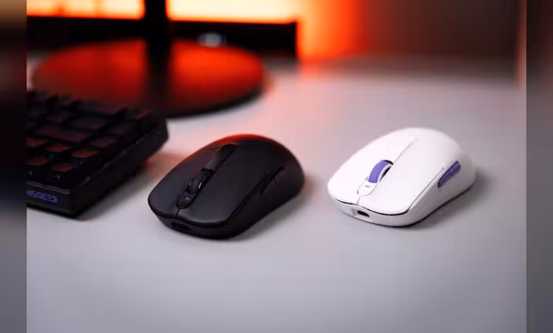 Akko Dash Master : une souris gaming de 40 g avec PAW 3955 et polling 8 kHz 1 Deux souris gaming sans fil, une noire et une blanche, posées sur un bureau avec clavier en arrière-plan