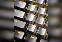 Gros plan de touches de clavier métalliques translucides Awekeys, avec Tab, Caps Lock, Shift, Win et Alt dorés.