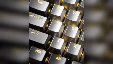Gros plan de touches de clavier métalliques translucides Awekeys, avec Tab, Caps Lock, Shift, Win et Alt dorés.