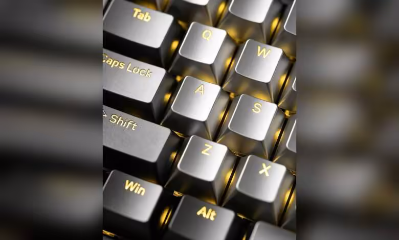Gros plan de touches de clavier métalliques translucides Awekeys, avec Tab, Caps Lock, Shift, Win et Alt dorés.