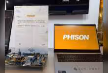Ordinateur portable avec logo Phison à l'écran à côté d'une carte électronique.
