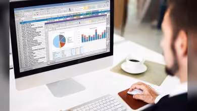 iMac Apple affichant Microsoft Excel avec tableaux, graphiques circulaires et histogrammes sur bureau de travail blanc