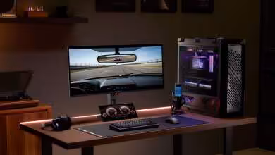 Setup gaming ASUS avec moniteur ultrawide, PC RGB et écran affichant une course automobile