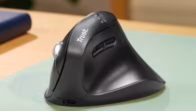 Souris verticale Trust Vyran sur un bureau en bois avec lumière naturelle.