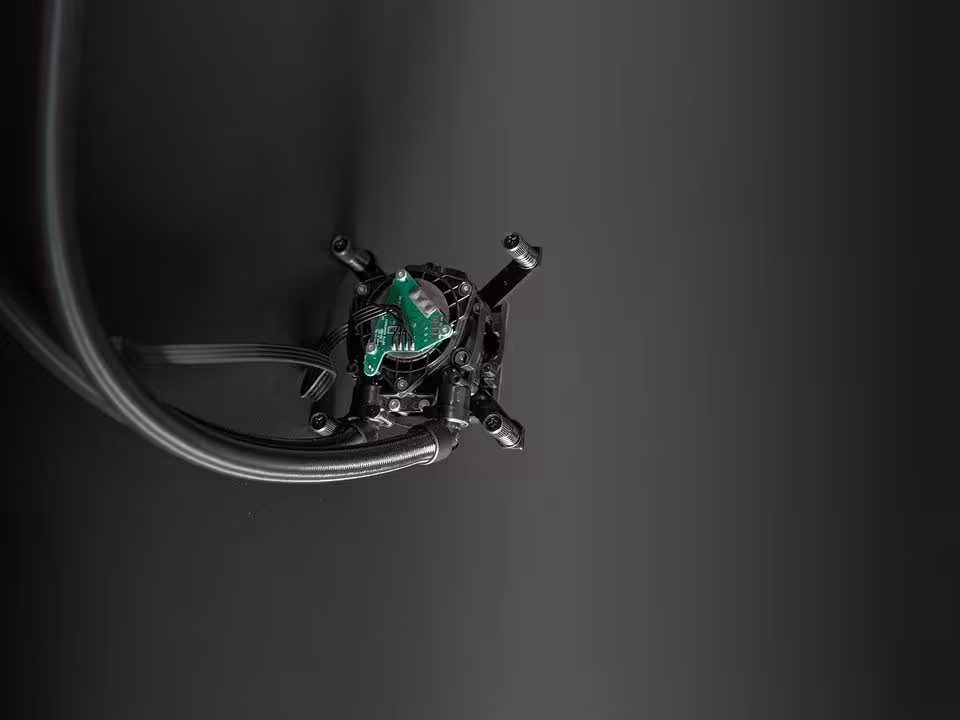 AIO Asetek Emma V3 : 1,5 °C de mieux et 45 % de bruit perçu en moins au Computex 2026 2 Bloc pompe Asetek Emma V3 vu de face avec carte électronique verte et tuyaux raccordés