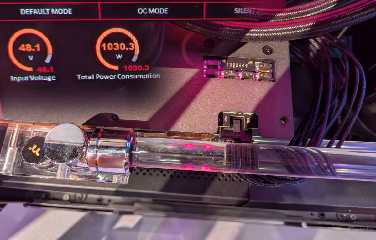 RTX 5090 à 48 V : ASUS pousse une carte modifiée à 1000 W via un seul câble 16 broches 2 Vue intérieure d'un PC avec indicateurs de performance GPU, éclairage rose sur fond sombre