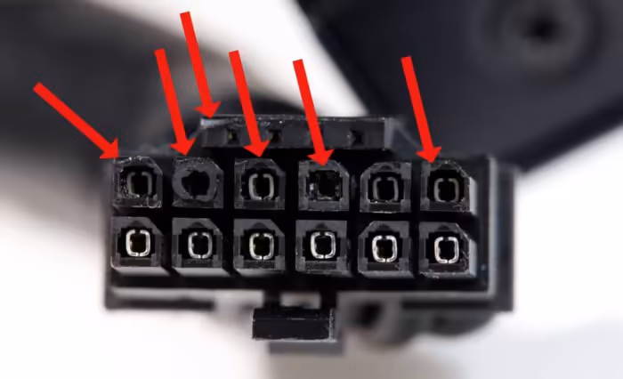 Connecteur d'alimentation avec plusieurs broches endommagées, flèches rouges indiquant les dégâts