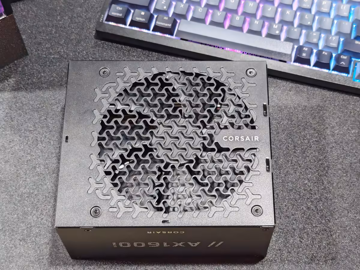 Corsair AX1600i SHIFT : 1600 W en 170 mm, la densité impose ses choix de câblage 2 Dos de l’alimentation Corsair AX1600i SHIFT avec grille motif tressé, vis de fixation et marquage Corsair.